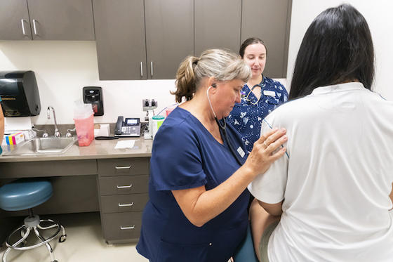 School of Nursing faculty providing medical care to a student in the Population Health Center. Photo by Shayla Brown